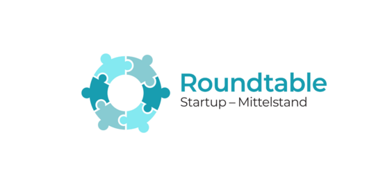 Logo von Roundtable Blauer Kreis aus Puzzlestücken, blauer Schriftzug auf weißem Hintergrund