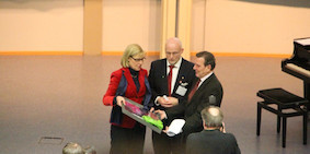Prof. Dr. Ursula Gather, Prof. Dr. Andreas Liening and former German Chancellor Gerhard Schröder stand in the Audimax during the presentation of the certificate for the New Year's Symposium 2012.